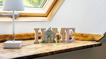 A window sill with a lamp, a wooden shelf, and decorative letters spelling 'HOME' with a small house model and plants.