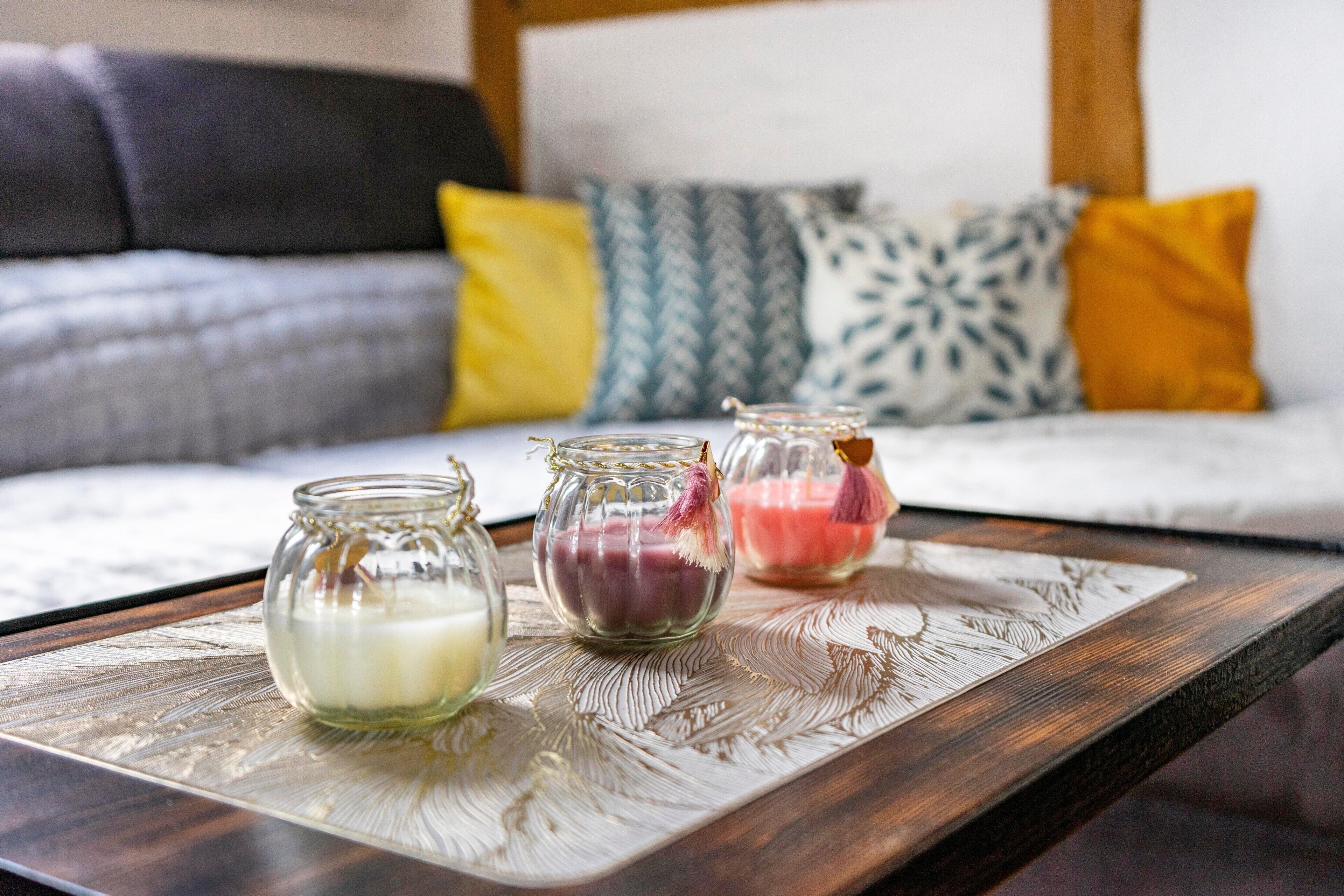 Une table basse en bois sur laquelle reposent trois bocaux en verre contenant des bougies.