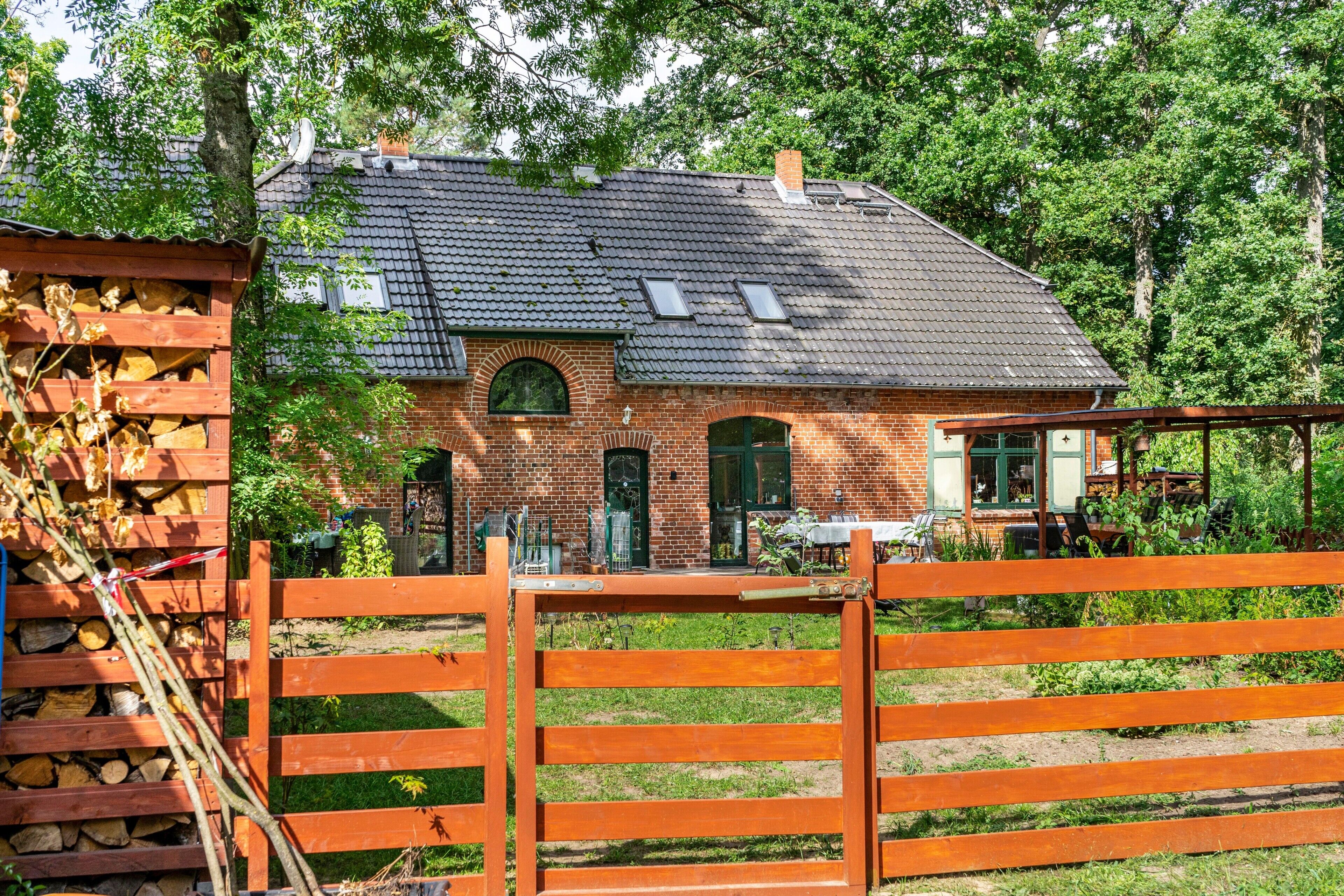 Ein Backsteinhaus mit Ziegeldach, Holzzaun und Garten.