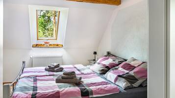 Une chambre à coucher avec un lit, une fenêtre, un radiateur et une table de chevet.