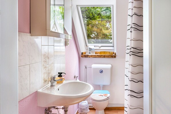 A bathroom with a sink, toilet, and window.
