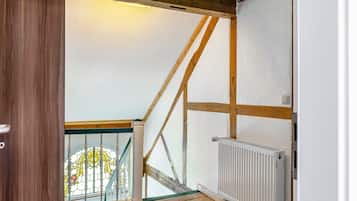 Une pièce dotée d’un plancher en bois, d’un radiateur blanc et d’une structure de poutres apparentes en bois au plafond.