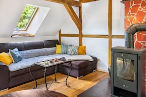 A cozy living room with a sofa, a table with candles, and a wood-burning stove.