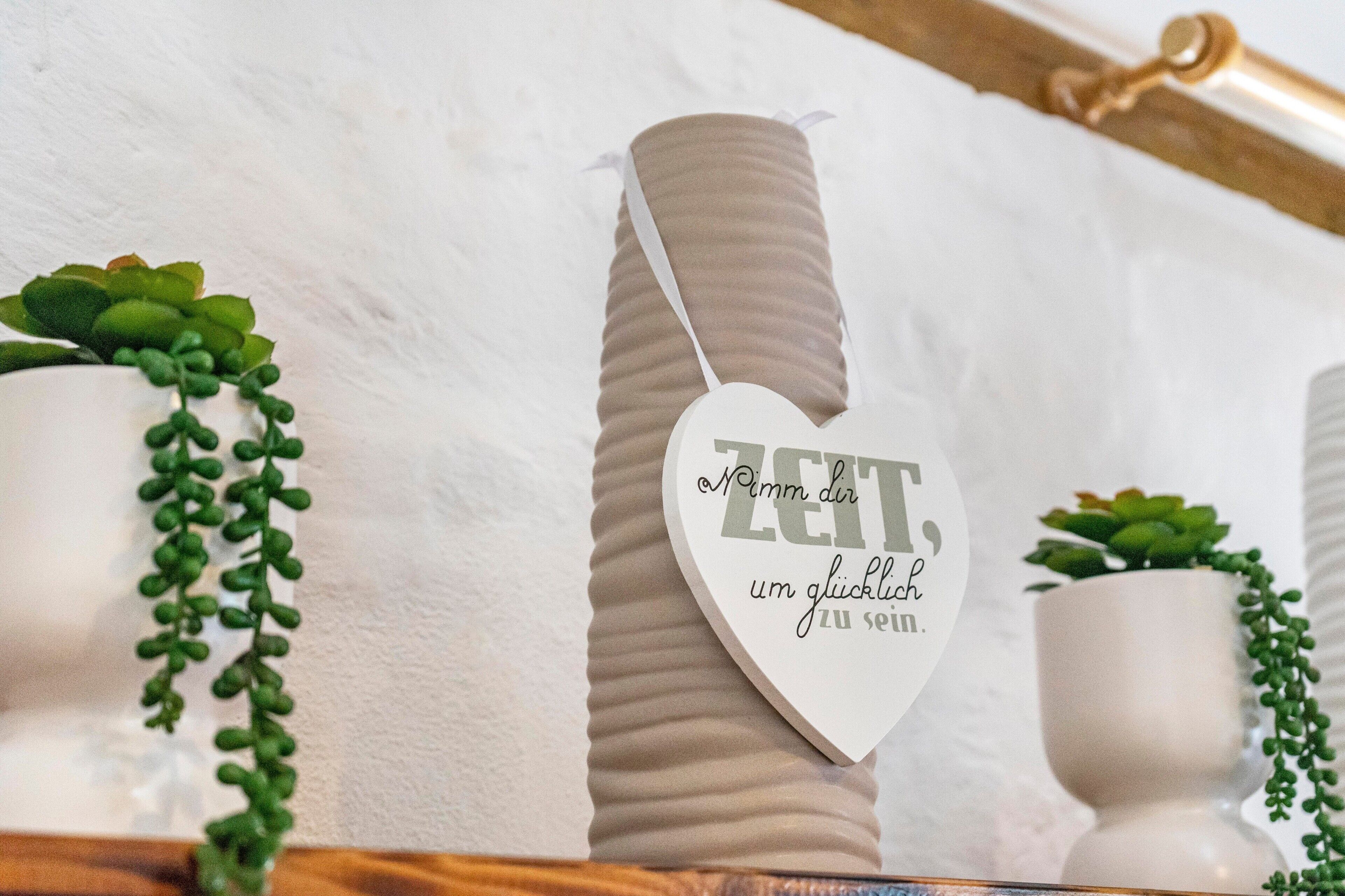 Une décoration en forme de cœur, ornée de texte, et entourée de plantes en pot.