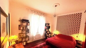 A bedroom with a bed, a bookshelf, a desk with a lamp, and a patterned wall. - 90-square-meter apartment in the city center, 10 minutes from the train station, 200 meters from the cathedral (Quimper)
