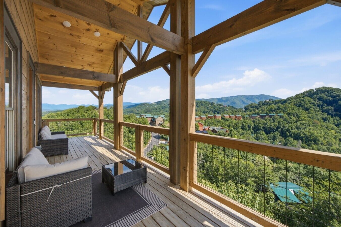 Une terrasse en bois, meublée de meubles en osier, avec vue sur un paysage montagneux.