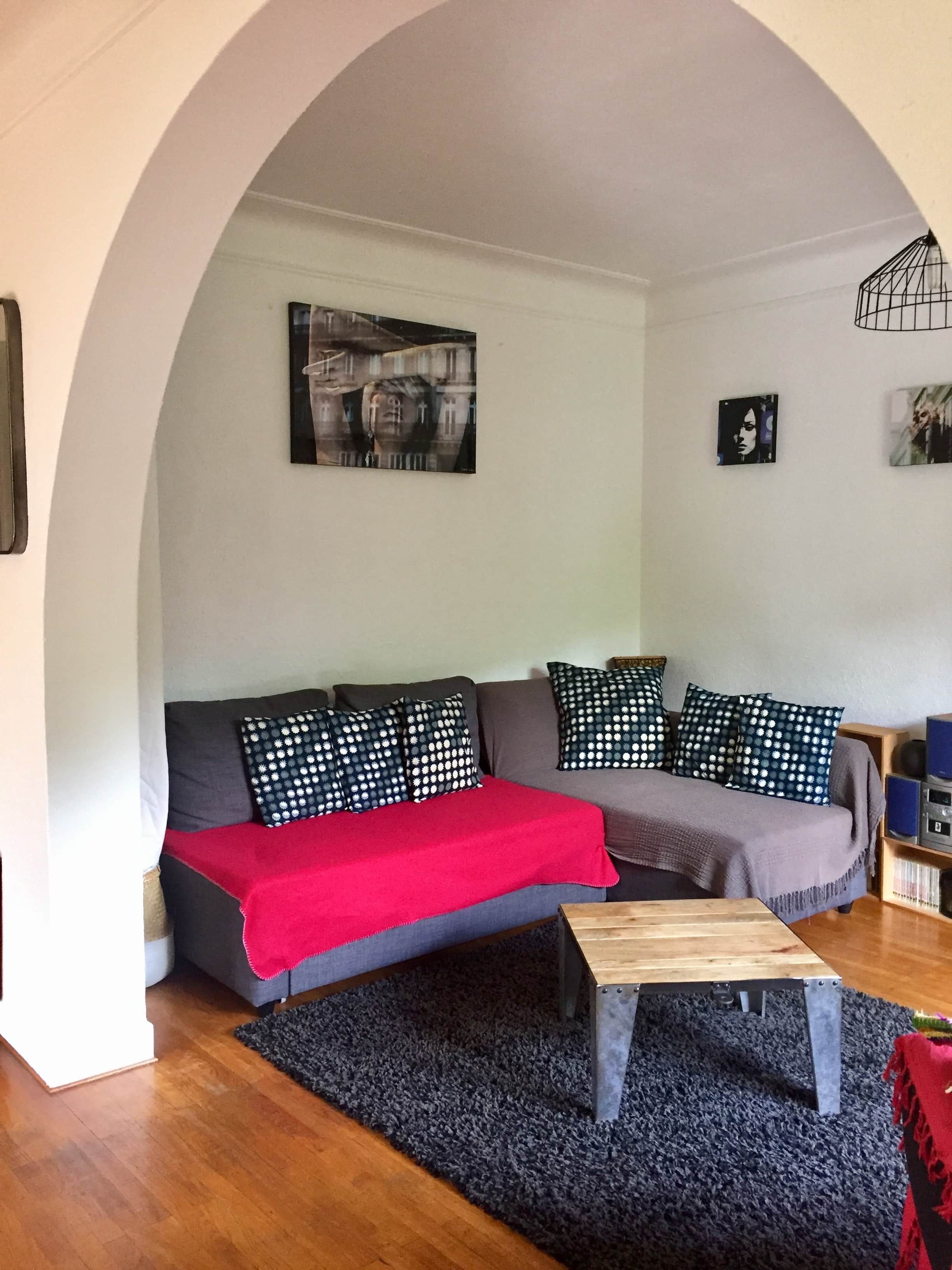 A living room with a sofa, a coffee table, and a red throw blanket.