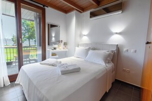 Ein Schlafzimmer mit einem Bett, einem Nachttisch, einem Spiegel und Blick ins Freie.