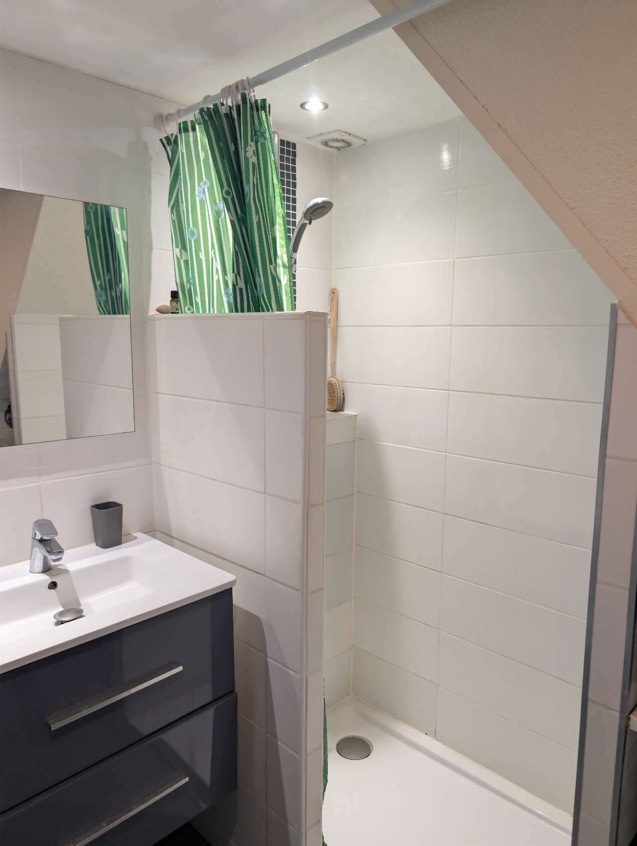 Ein modernes Badezimmer mit Waschbecken, Spiegel und Dusche.