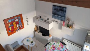 Ett kompakt bostadsutrymme med ett litet kök, en matplats och en tv.