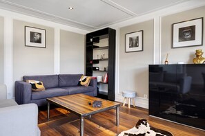 A modern living room with a grey sofa, a wooden coffee table, a black entertainment unit, and a cowhide rug. - Holiday Home 'Esprit Chic-Calme-Climatisation' with Private Garden, Wi-Fi and Air Conditioning (Pessac)