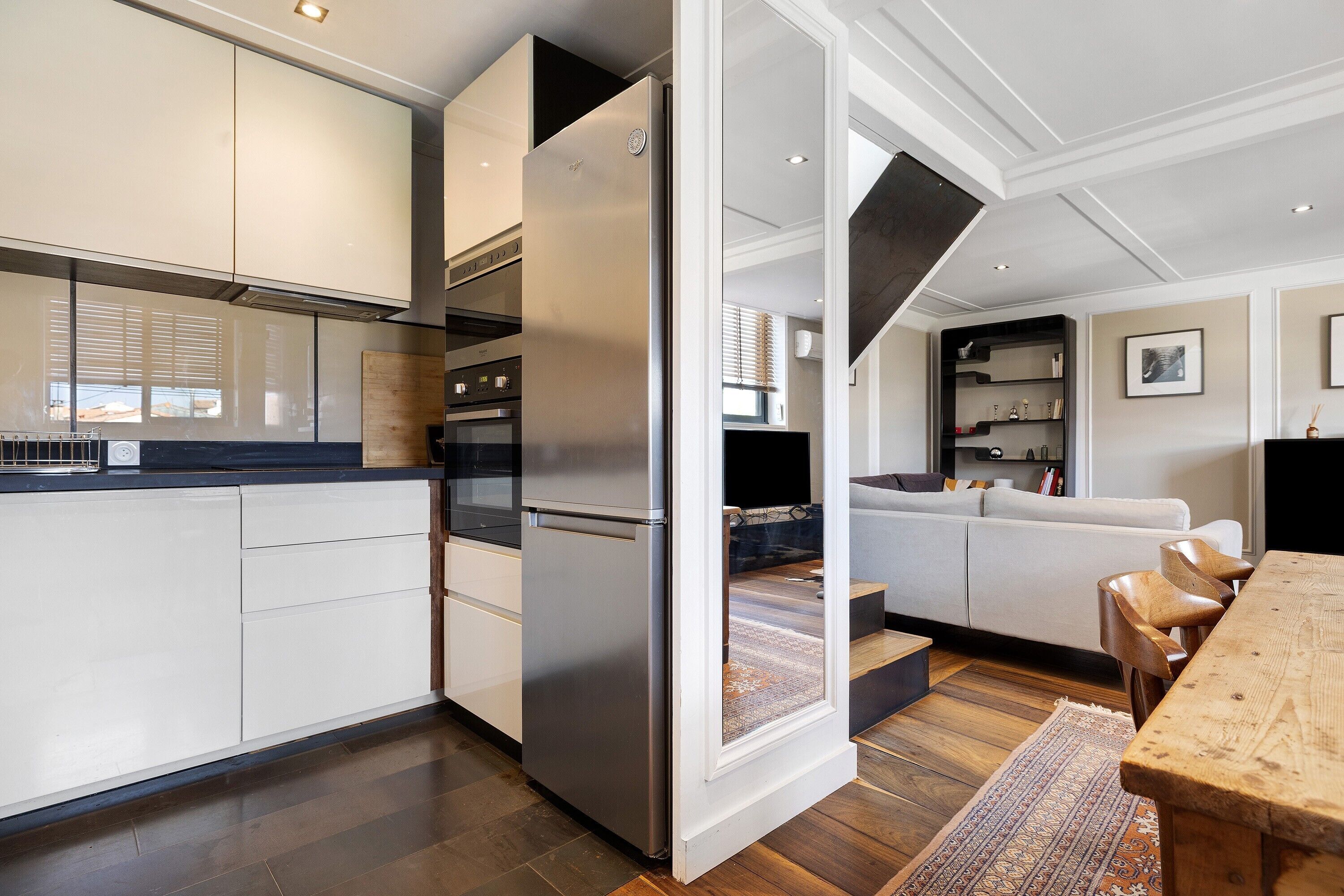 A modern kitchen with white cabinetry, a stainless steel refrigerator, and a built-in oven.