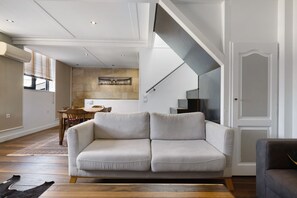 A modern living room with a sofa, a dining table, and a staircase. - Holiday Home 'Esprit Chic-Calme-Climatisation' with Private Garden, Wi-Fi and Air Conditioning (Pessac)