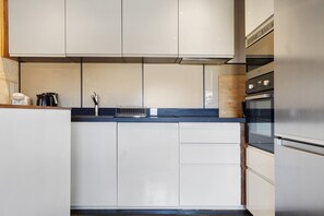 A compact kitchen with a built-in oven, a coffee machine, and a kettle. - Holiday Home 'Esprit Chic-Calme-Climatisation' with Private Garden, Wi-Fi and Air Conditioning (Pessac)