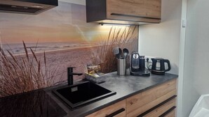 Una cucina con lavello nero, mobili in legno, una macchina da caffè e una lampada a parete.