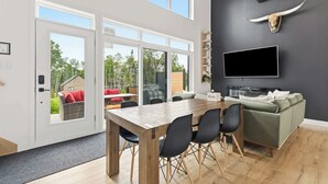 En modern inredning med ett matområde, en soffa, en TV som är monterad på väggen och ett stort fönster.