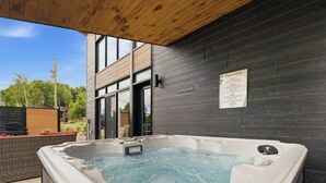 Ett bubbelbad utomhus, med en träpergola ovanför och en skylt på väggen.