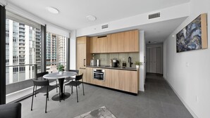 Una cocina moderna con comedor, ventanas amplias y vistas a edificios altos.