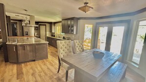 Cocina con isla central, armarios de madera oscura y una mesa de comedor con banco.