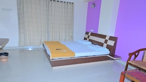 Ein Schlafzimmer mit Bett, Stuhl, Schreibtisch und Vorhang.