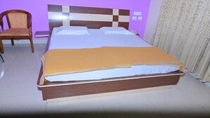 Ein Bett mit Holz-Kopfteil, ein Stuhl und ein Vorhang.