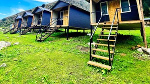 Une rangée de cabanes en bois, dotées d’escaliers extérieurs et d’un panneau solaire fixé sur un poteau.