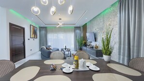 A modern dining room with a long table, chairs, and a television in the background. - AKOA Villa at THE HIDDEN DOMUS, Premium, Cozy and Spacious 4bed Villa (Accra)