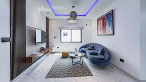 A modern living room with a sofa, a coffee table, a TV, and a large window. - AKOA Villa at THE HIDDEN DOMUS, Premium, Cozy and Spacious 4bed Villa (Accra)