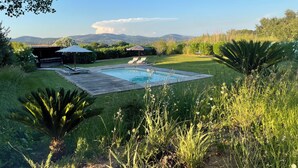 Un jardin avec une piscine, des chaises longues et une vue sur les montagnes.