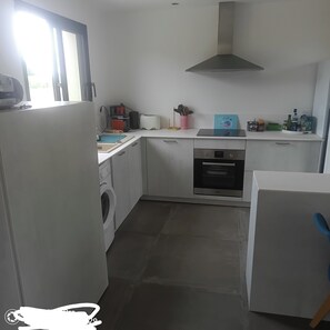 A compact kitchen with a washing machine, a built-in oven, and a coffee maker. - Apartment (Marseillan)