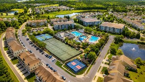 A residential area with multiple apartment buildings, a tennis court, and a swimming pool. - Bayside 3BR Condo | Pool, Golf & Beach Access (Selbyville)