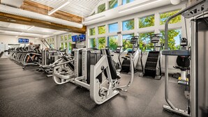 A gym with treadmills, weight machines, and a TV screen. - Bayside 3BR Condo | Pool, Golf & Beach Access (Selbyville)