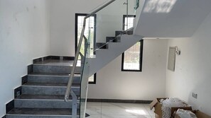 Eine Treppe mit Glasgeländern, Fliesenboden und einem Fenster.