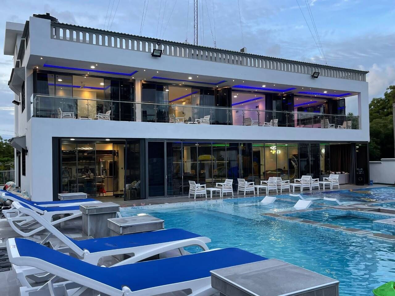 A modern hotel with a pool area, lounge chairs, and a two-story building.
