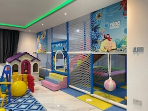 Ein Kinderspielbereich mit Rutsche, Kletterstufen und Bällebad.