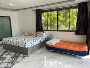 Ein Schlafzimmer mit einem Bett, einer Schlafcouch, einem Fenster mit Vorhängen, einem Deckenventilator und einem gefliesten Boden.