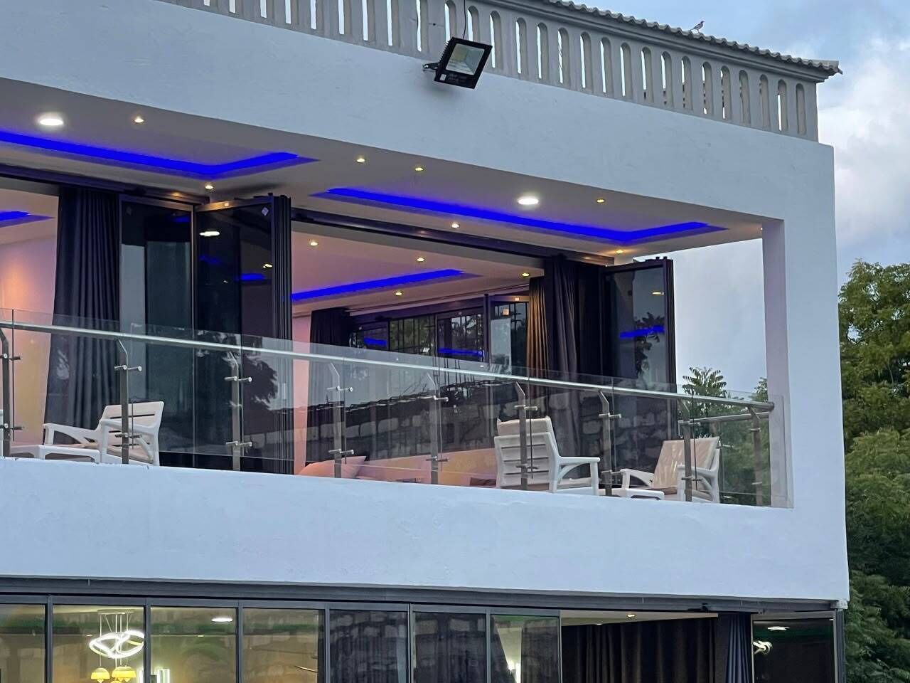 A modern building with a balcony, glass railings, and a flat roof.