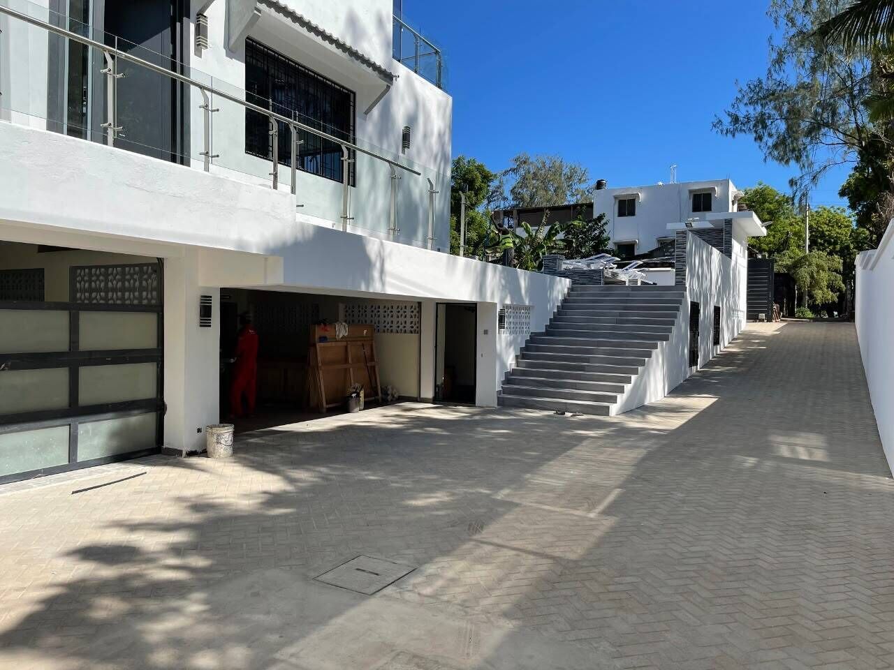 A modern building with a garage, a staircase, and a paved walkway.