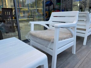 Ein weißer Stuhl mit Kissen, ein weißer Tisch und eine Glastrennwand.