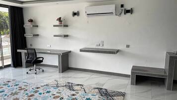 A modern room with a desk, chair, air conditioning unit, and decorative shelves.