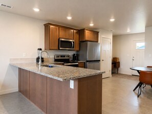 A kitchen with wooden cabinets, stainless steel appliances, a granite countertop, and recessed ceiling lights. - 1-bedroom house in Stanfield (Stanfield)