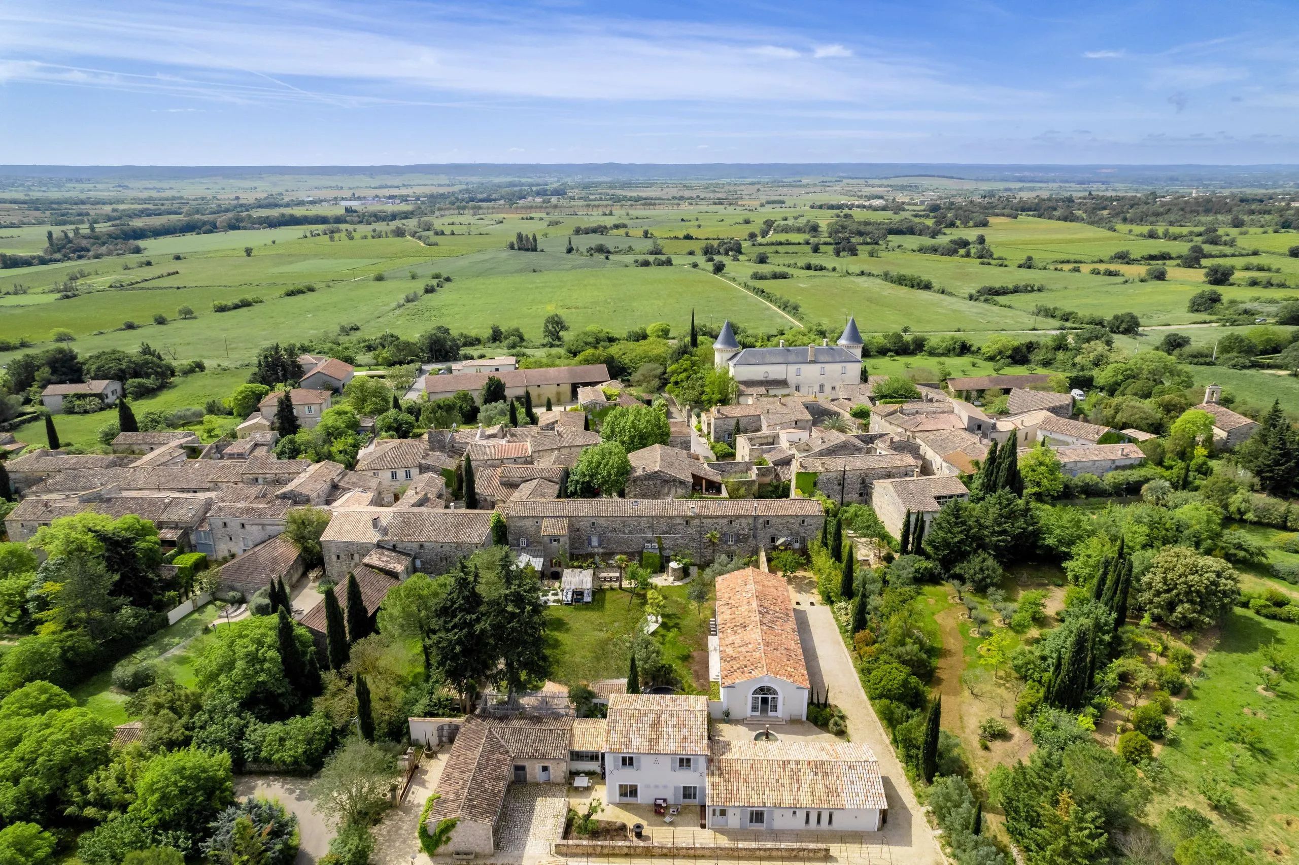 A historic village with stone buildings, a church, and a castle in the background.