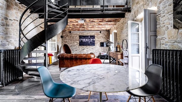 Une pièce dotée d’un escalier en colimaçon, d’une table ronde en marbre et d’un canapé rouge.