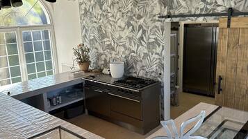 A modern kitchen with a central island, stainless steel appliances, and a decorative leaf-patterned wall.