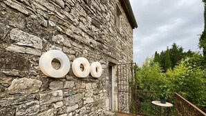 Un bâtiment en pierre avec trois grands éléments circulaires sur le mur, une petite porte et un balcon doté d’une balustrade.