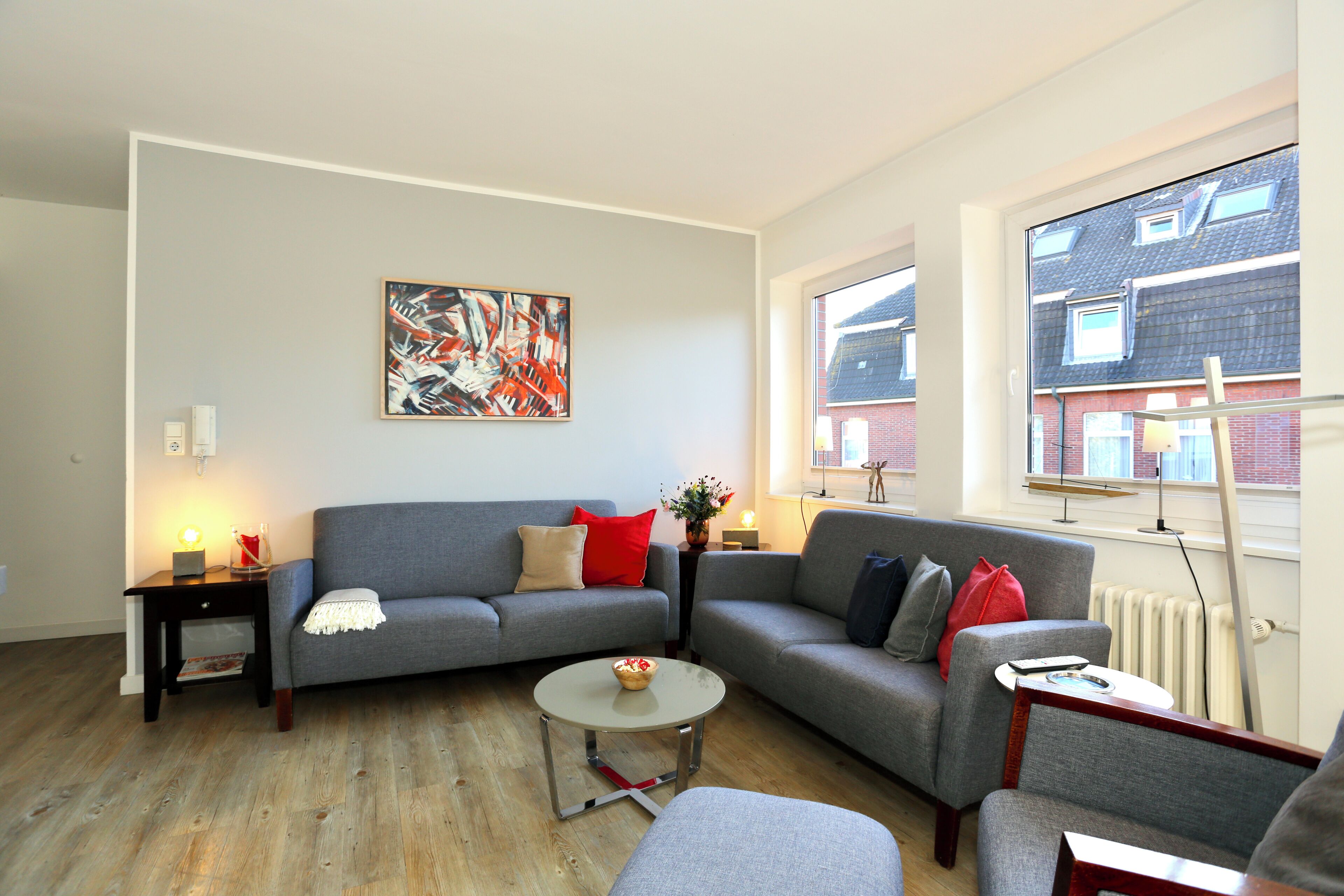 A modern living room with a grey sofa, a coffee table, and a painting on the wall.