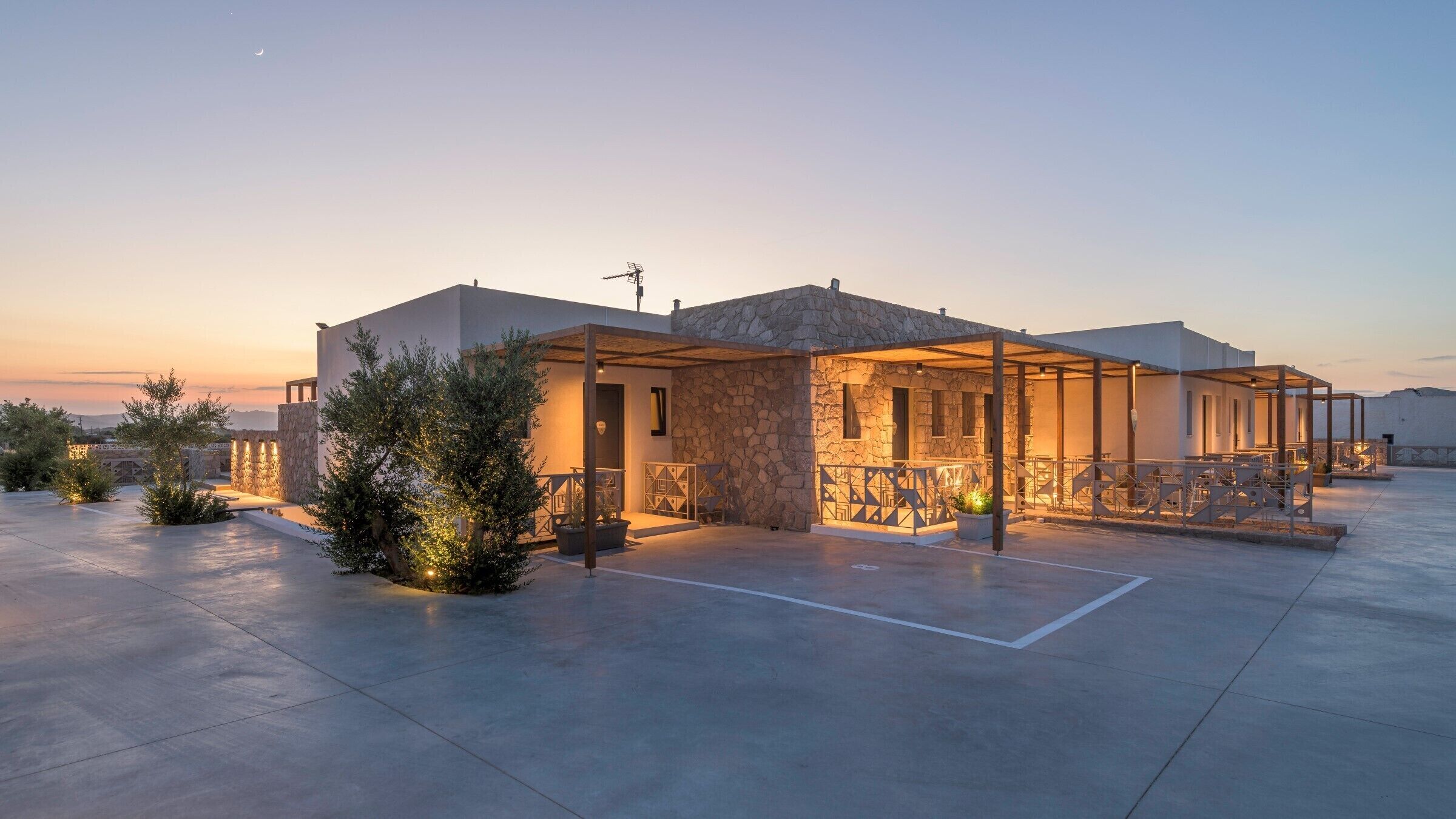 Een modern gebouw met een stenen gevel, een overdekt terras en uitzicht op het omliggende landschap.