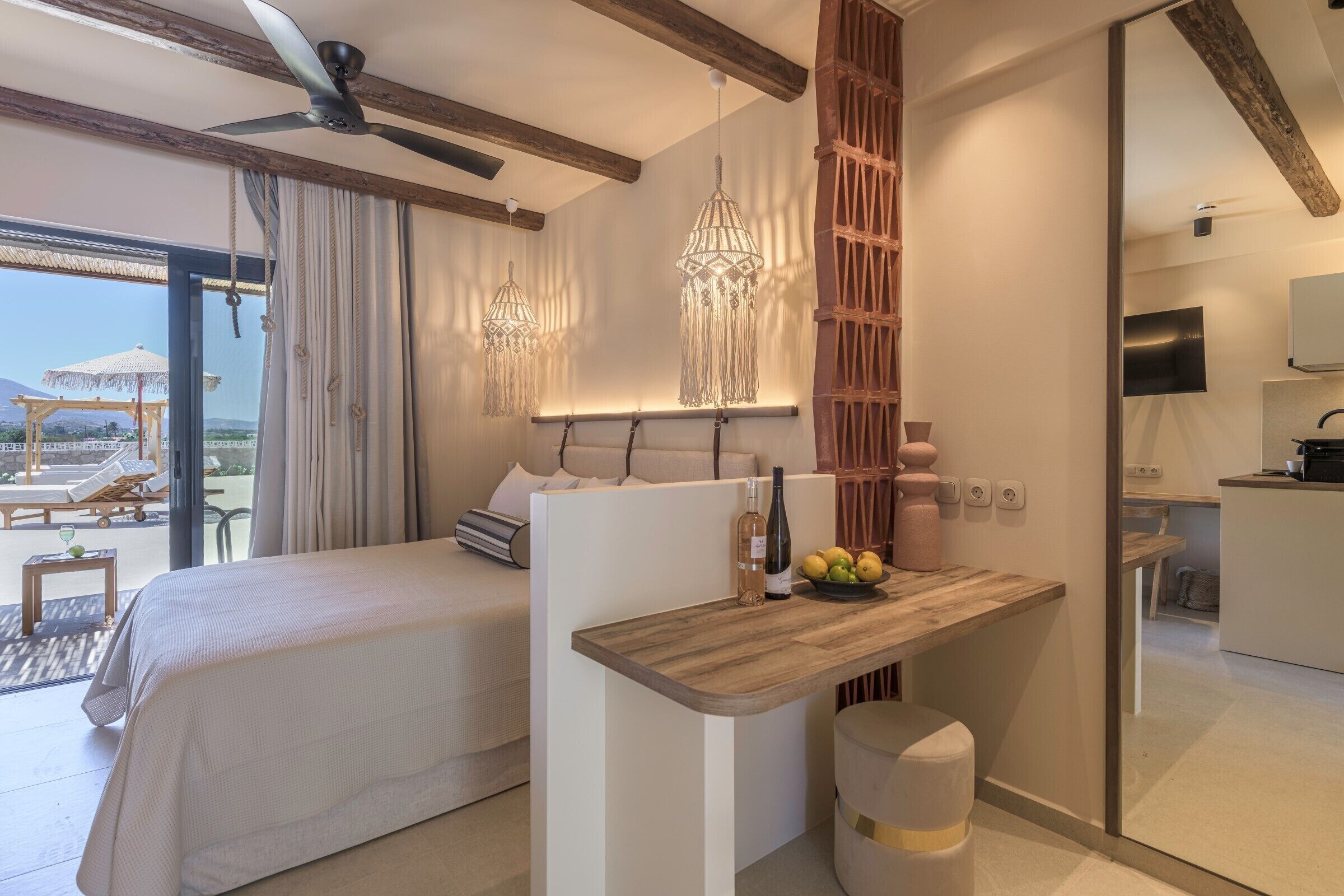 Una habitación de hotel con una cama, un escritorio de madera, una botella y un frutero.