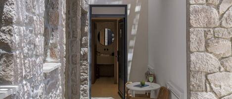 A stone-walled corridor with a staircase leading to a second-floor balcony.