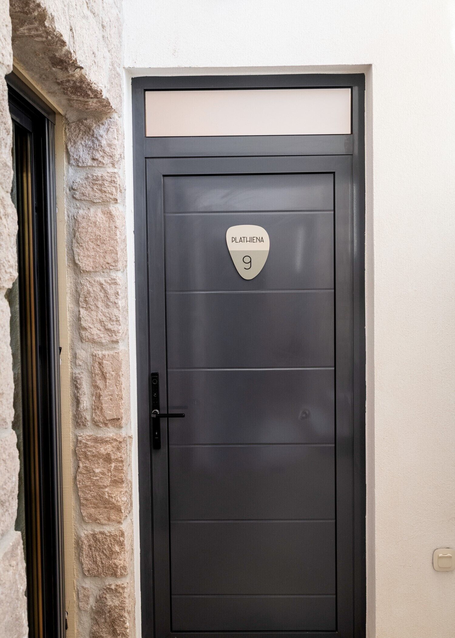 A door with a sign reading 'PLATH-HIENNA 9' and a black door handle.
